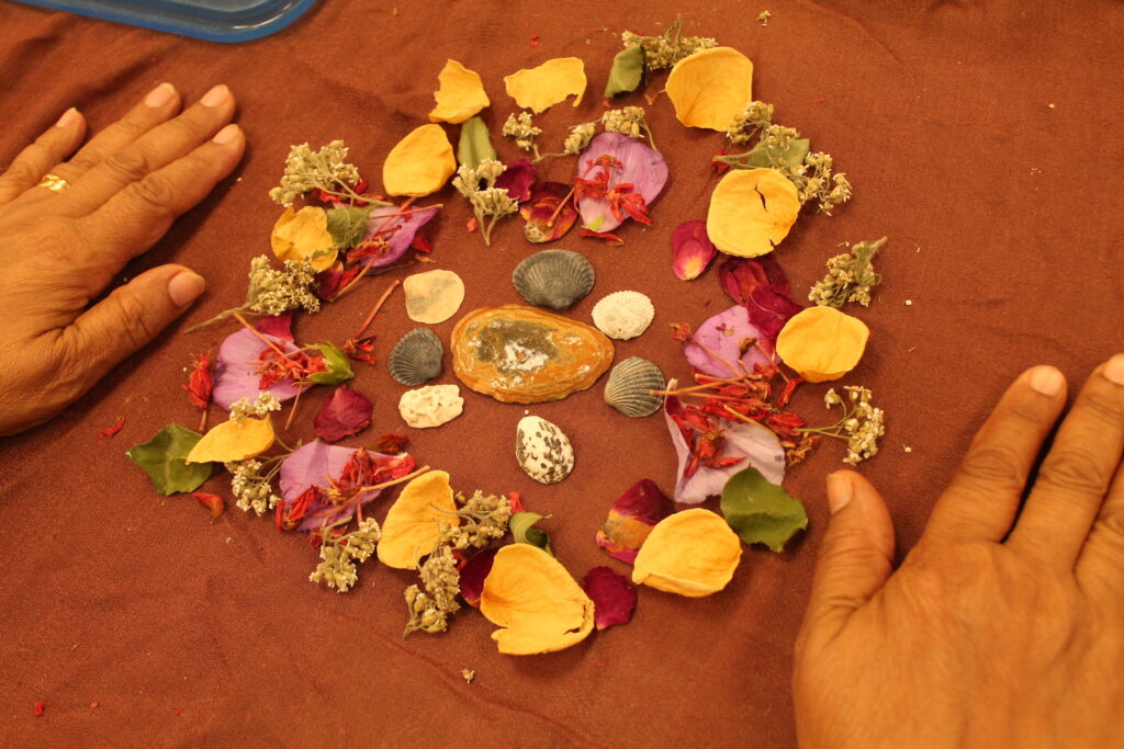 womans hands on brown fabric with mandala made with natural materials